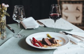 Erfrischend anders: Reh trifft Flusskrebs, © Niederösterreich Werbung/David Schreiber Elegantes Abendessen mit Fleisch, Flusskrebs und Rotwein auf gedecktem Tisch.