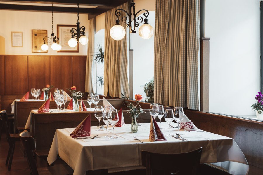 Einkehren in Krumbach, © Niederösterreich Werbung/David Schreiber Gemütliches Restaurant mit gedeckten Tischen, Weingläsern und Blumenvasen.