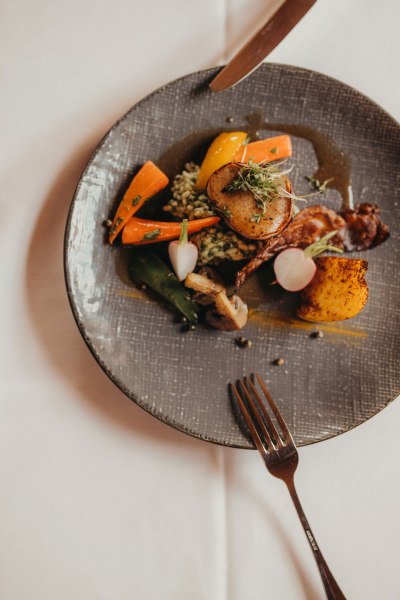 Rosa Schweinsfilet im Bauchspeckmantel mit Bärlauchrisotto, © Niederösterreich Werbung/Daniela Führer Ein Teller mit Schweinsfilet im Speckmantel, Bärlauchrisotto und Gemüse.