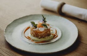 Alpensaibling-Tatar, Sauerampfer-Kerbelsud, © Niederösterreich Werbung/Sophie Menegaldo Gourmetgericht auf einem Teller mit Lachs, Kräutern und Soße dekoriert.
