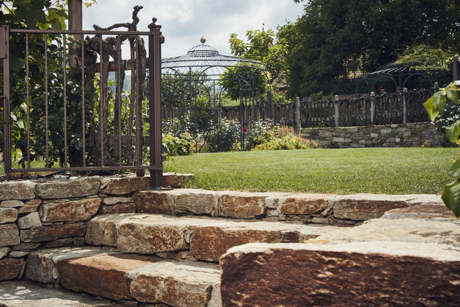 Natürlich romantischer Garten, © Niederösterreich Werbung/Andreas Hofer Steintreppe im Garten mit Metallzaun und Pavillon im Hintergrund.