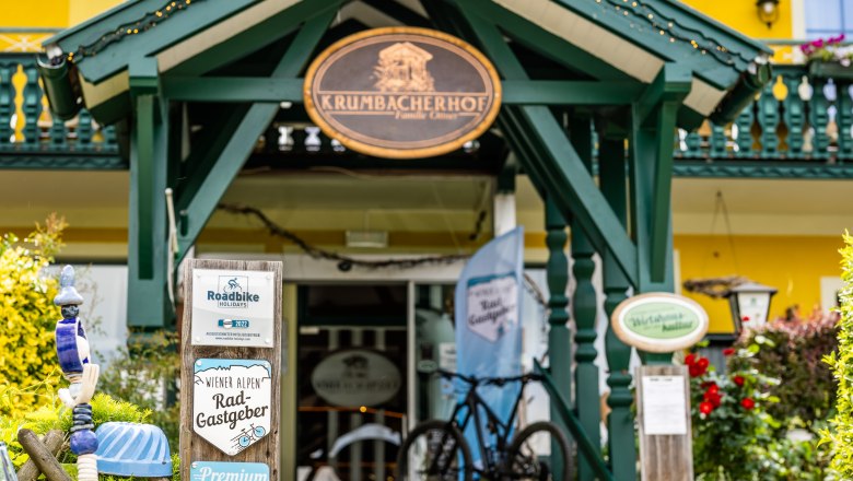 Eingang des Krumbacherhofs mit Fahrrad und Schildern für Radfahrer.