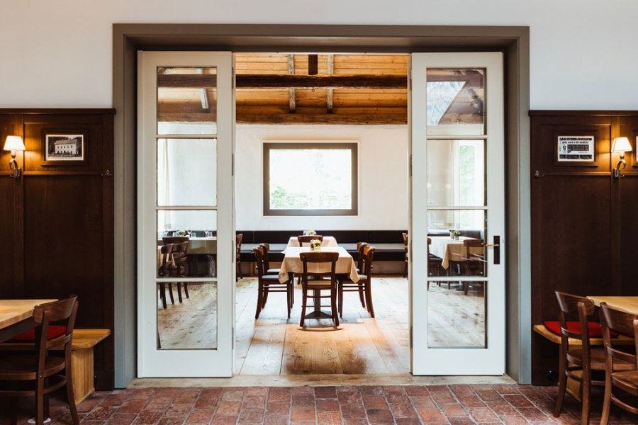 Gem&uuml;tliches Restaurant mit Holzm&ouml;beln und gro&szlig;en Fenstern.