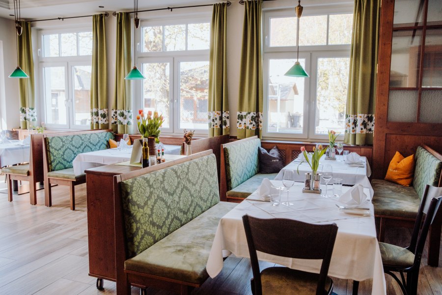 Gemütliches Restaurant mit grünen Sitzbänken und Tischdekoration.