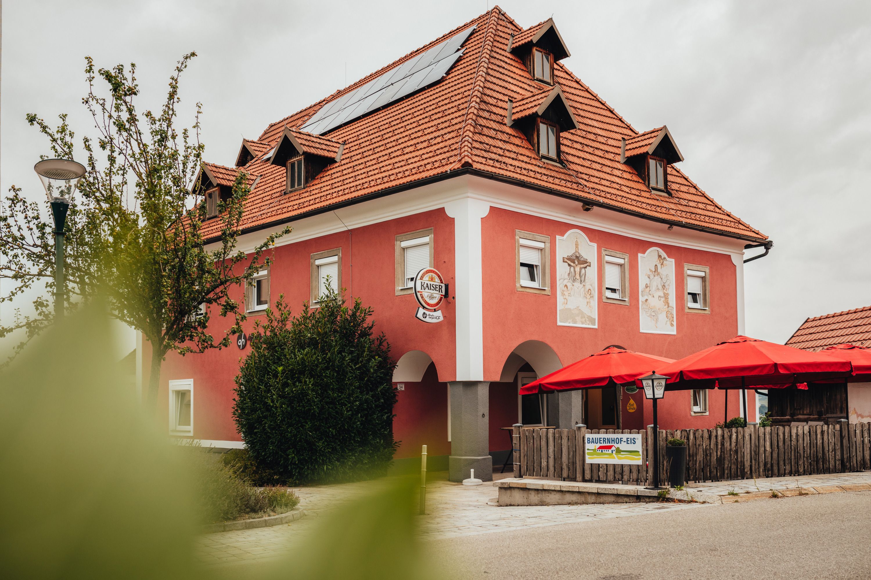 A red building with red sunshades and solar panels on the roof.
