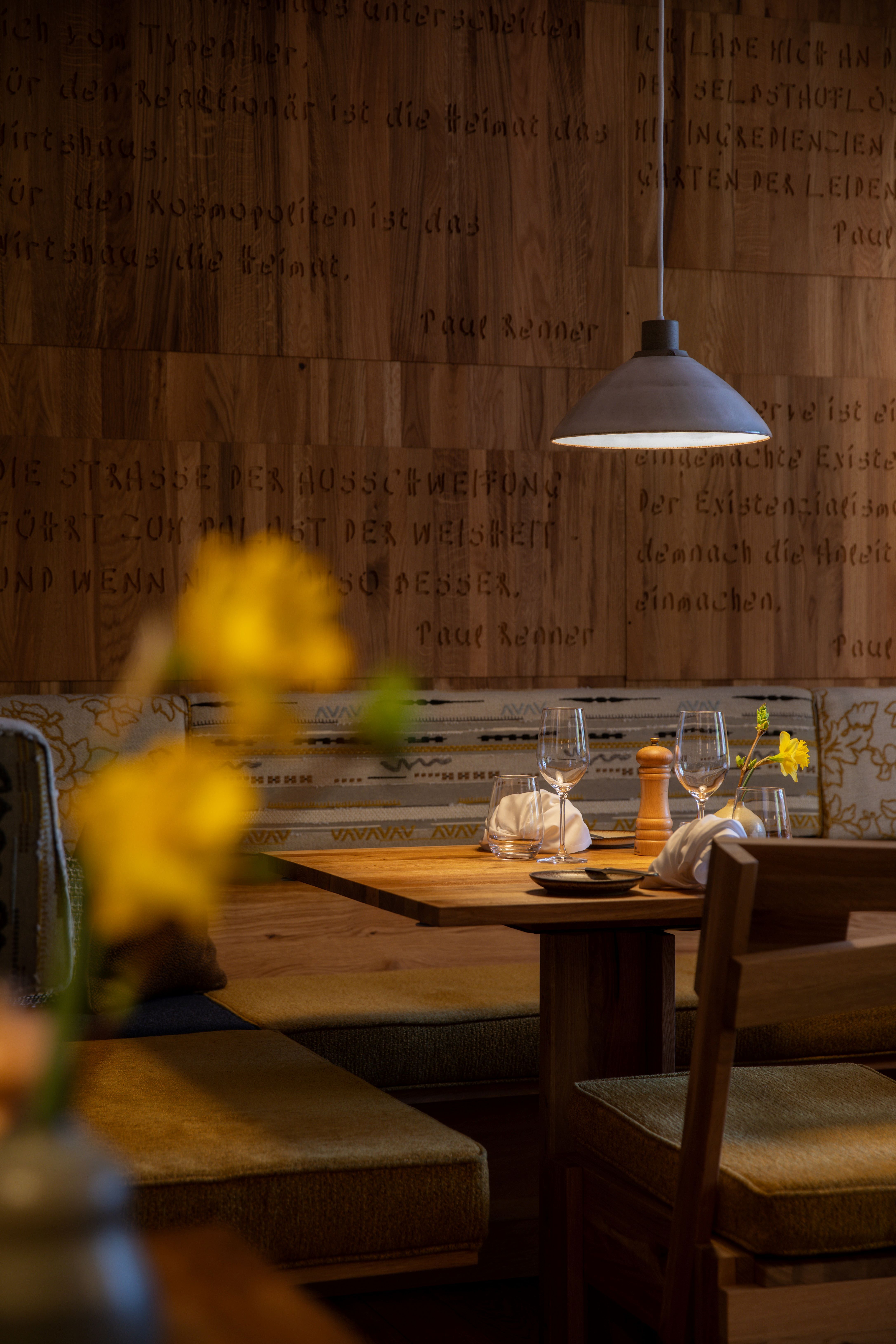 Gemütlich gedeckter Tisch in einem Restaurant mit Holzwänden und hängender Lampe.