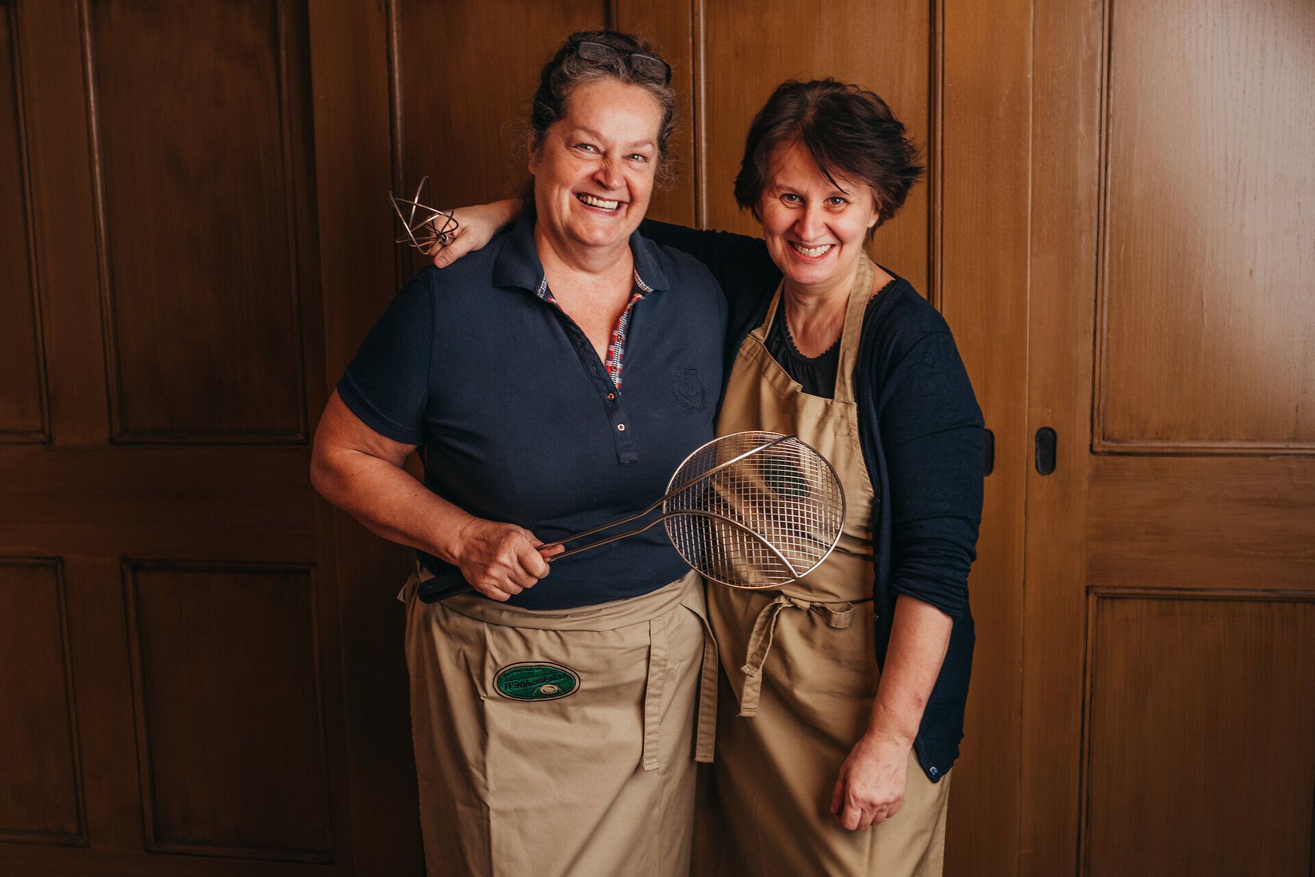 Zwei freundliche Gastgeberinnen strahlen in ihrer gemütlichen Umgebung, bereit, die Besucher mit regionalen Köstlichkeiten zu verwöhnen. Die Atmosphäre ist herzlich und einladend, perfekt für einen entspannten Aufenthalt im Mostviertel.