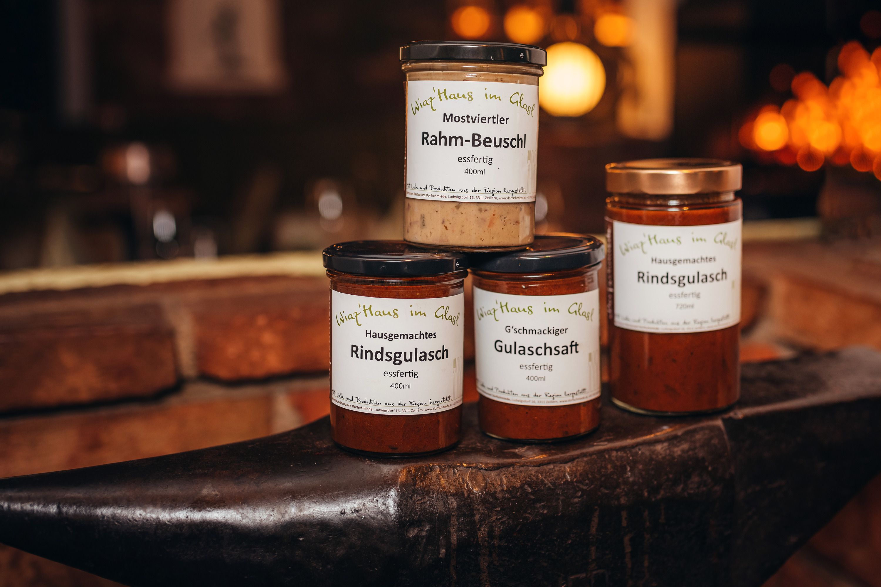 Drei Gläser mit Fertiggerichten auf einem Amboss, beschriftet mit 'Wirtshaus im Glas'.