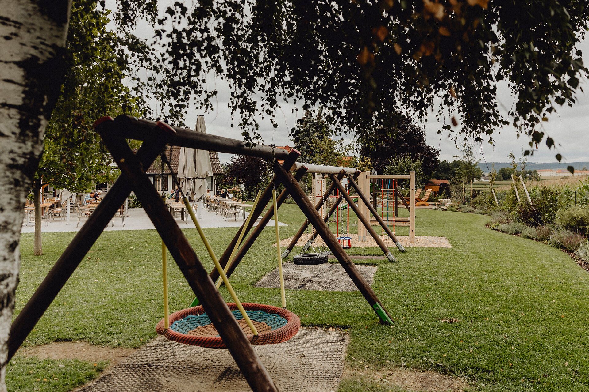 Ein einladender Spielplatz umgeben von saftigem Grün bietet Familien die perfekte Gelegenheit, die Natur zu genießen. Die schwingenden Schaukeln und die bunten Spielgeräte laden Kinder zum Spielen und Entdecken ein, während die ruhige Atmosphäre des Waldviertels für entspannte Momente sorgt.