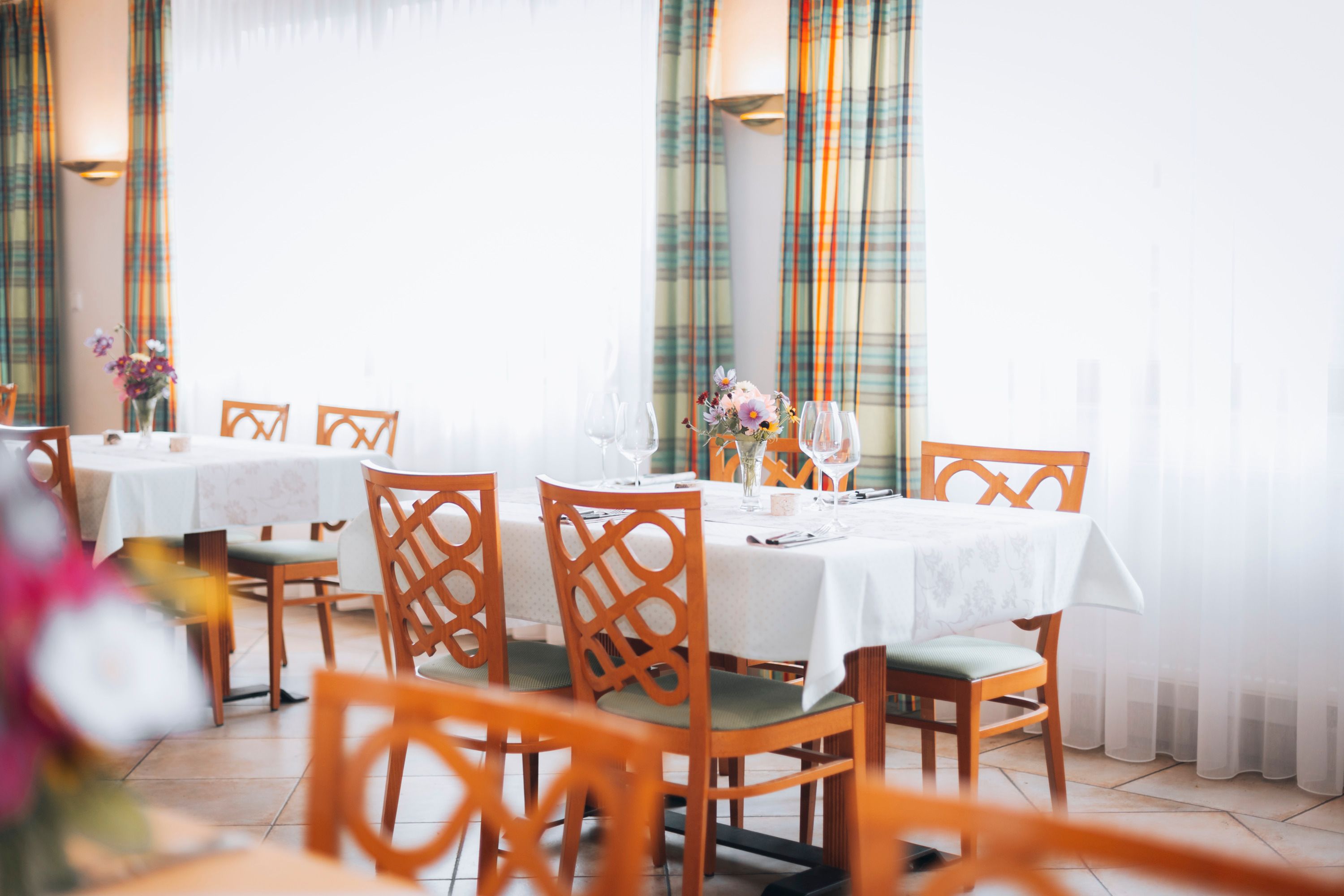 Elegant restaurant with laid tables, flower arrangements and wine glasses.