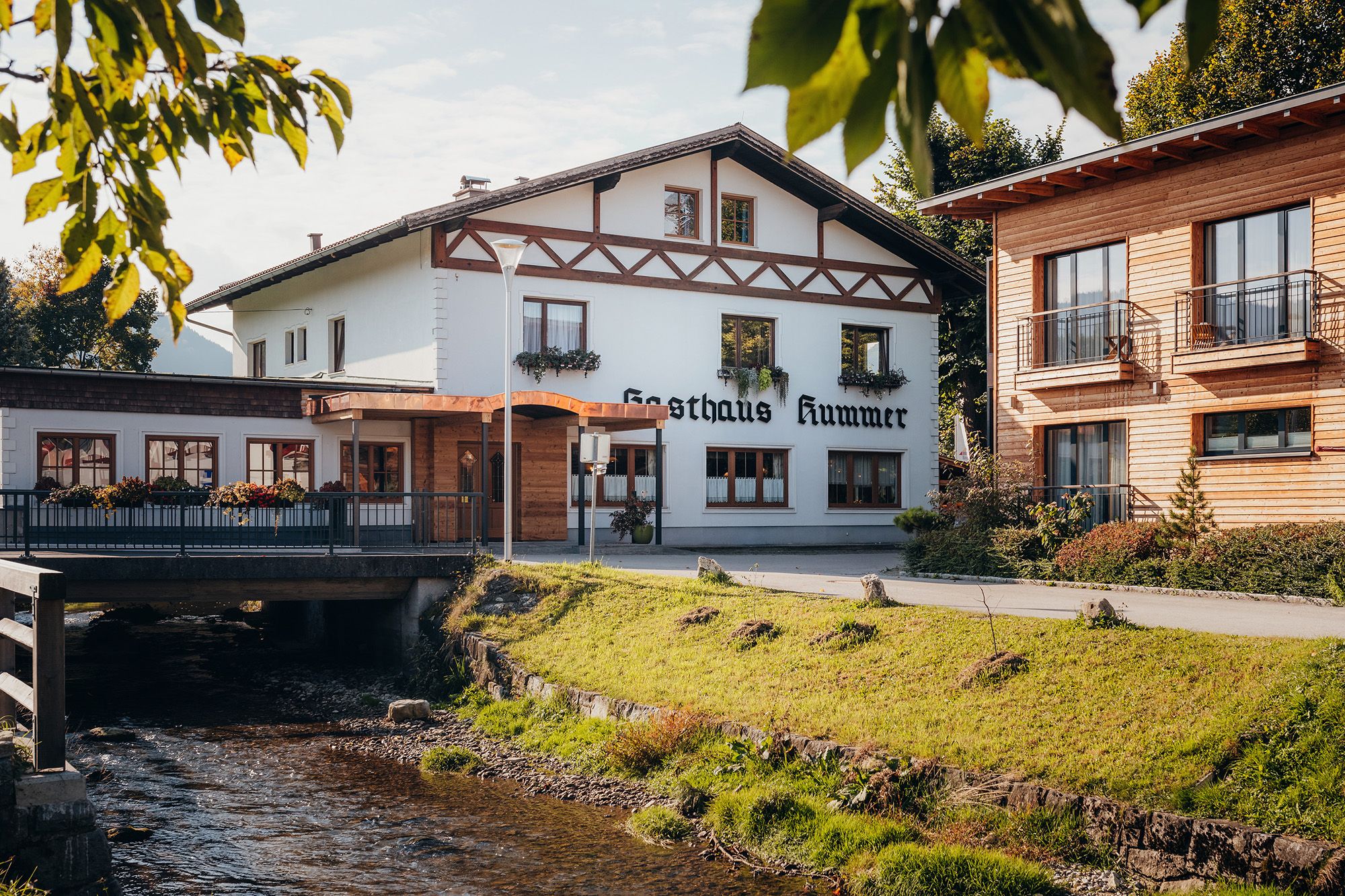 Ein traditionelles Gasthaus mit weißer Fassade und Holzverzierungen neben einem Bach.