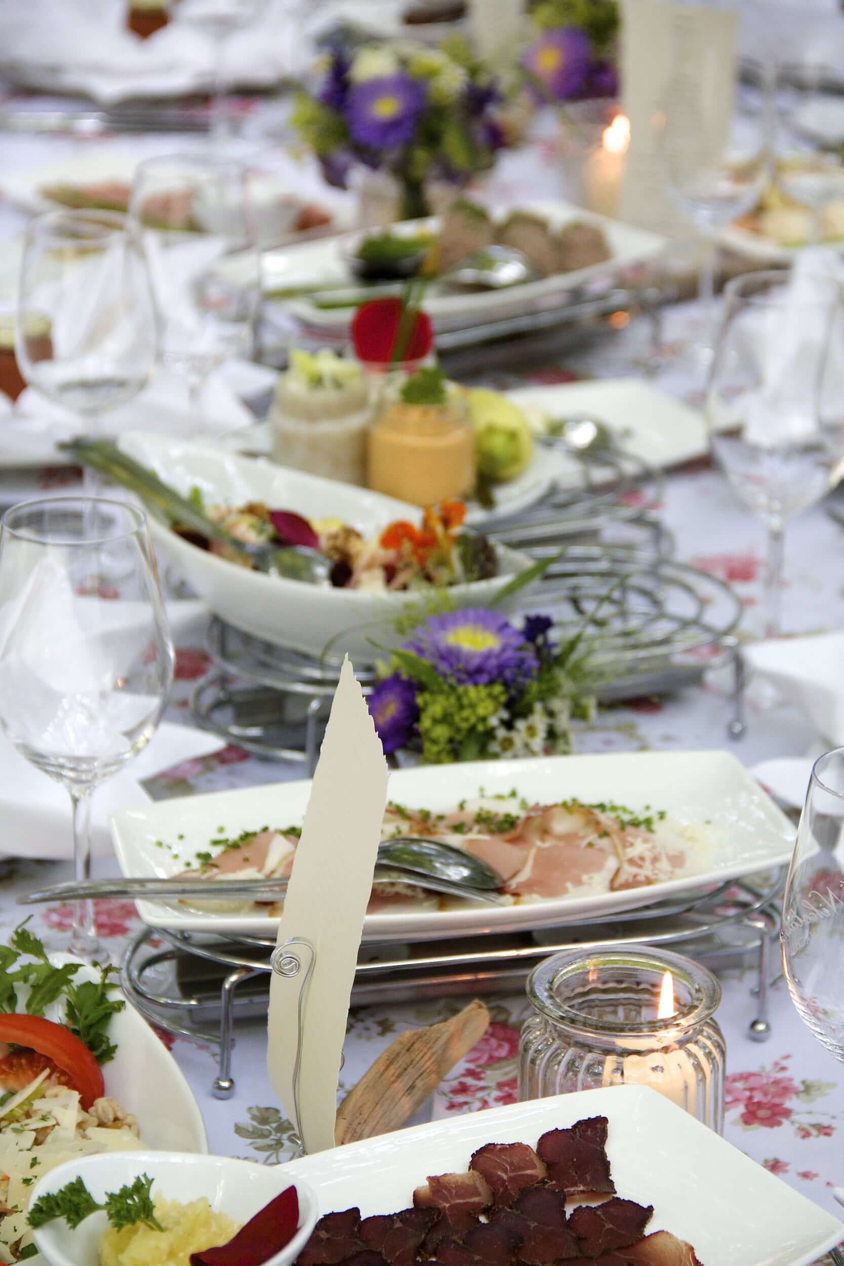 Ein gedeckter Tisch mit verschiedenen Speisen und Blumenarrangements.