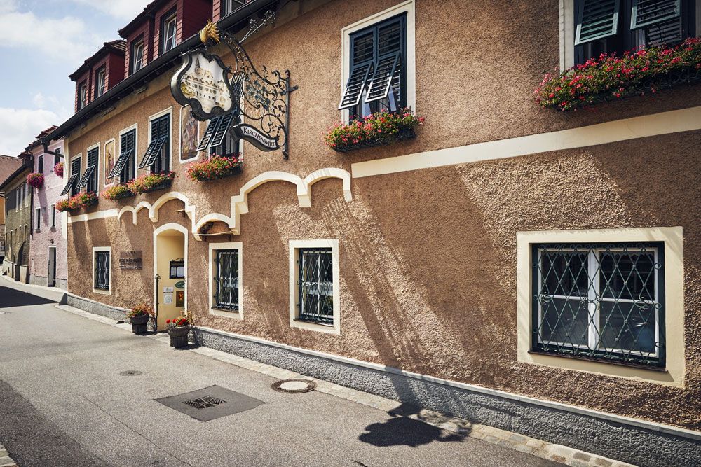 Traditionelles Gasthaus mit Blumenkästen und dekorativem Schild.