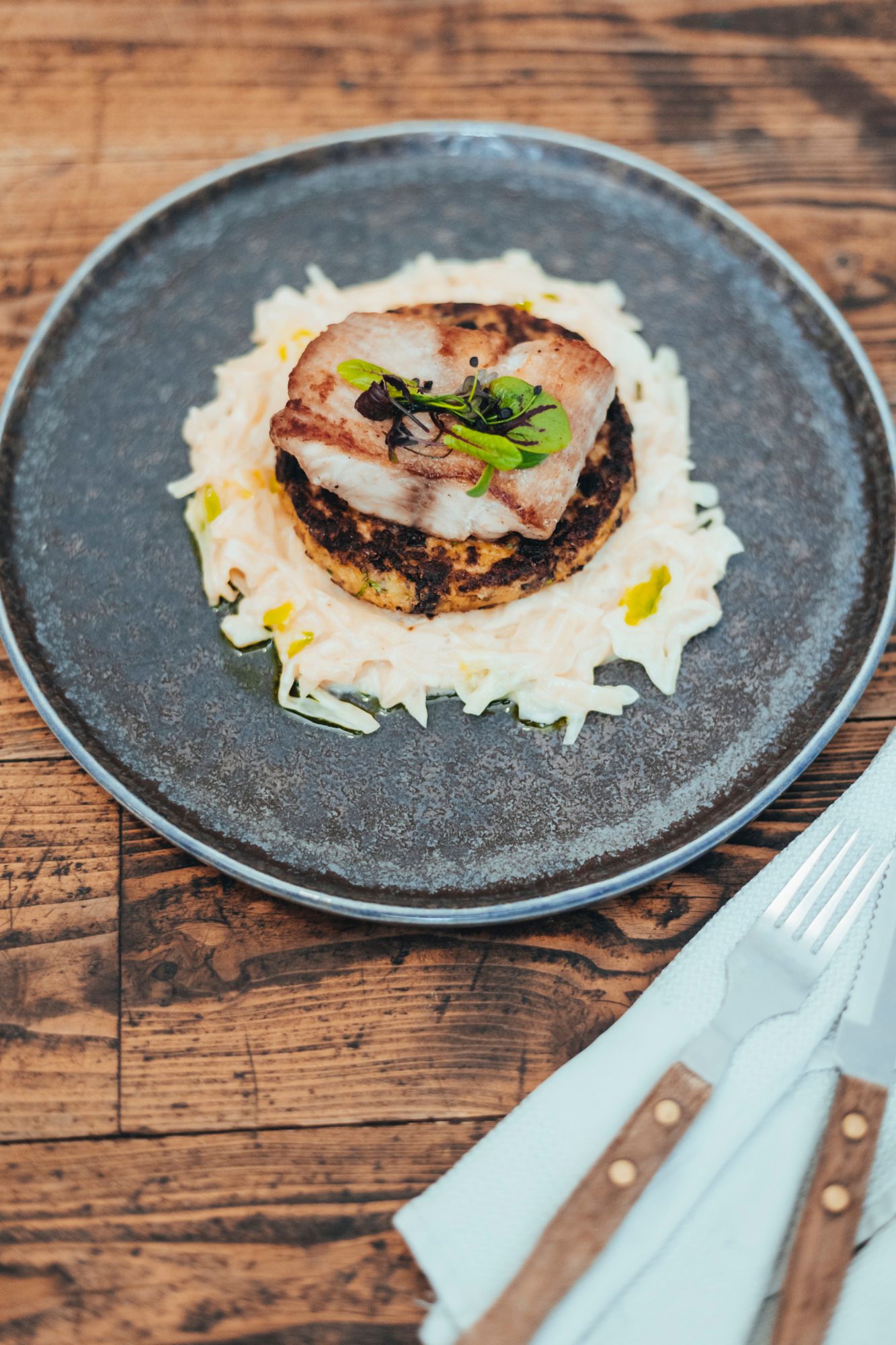 Ein Gericht mit Fisch auf Rösti und Kraut auf einem Teller.