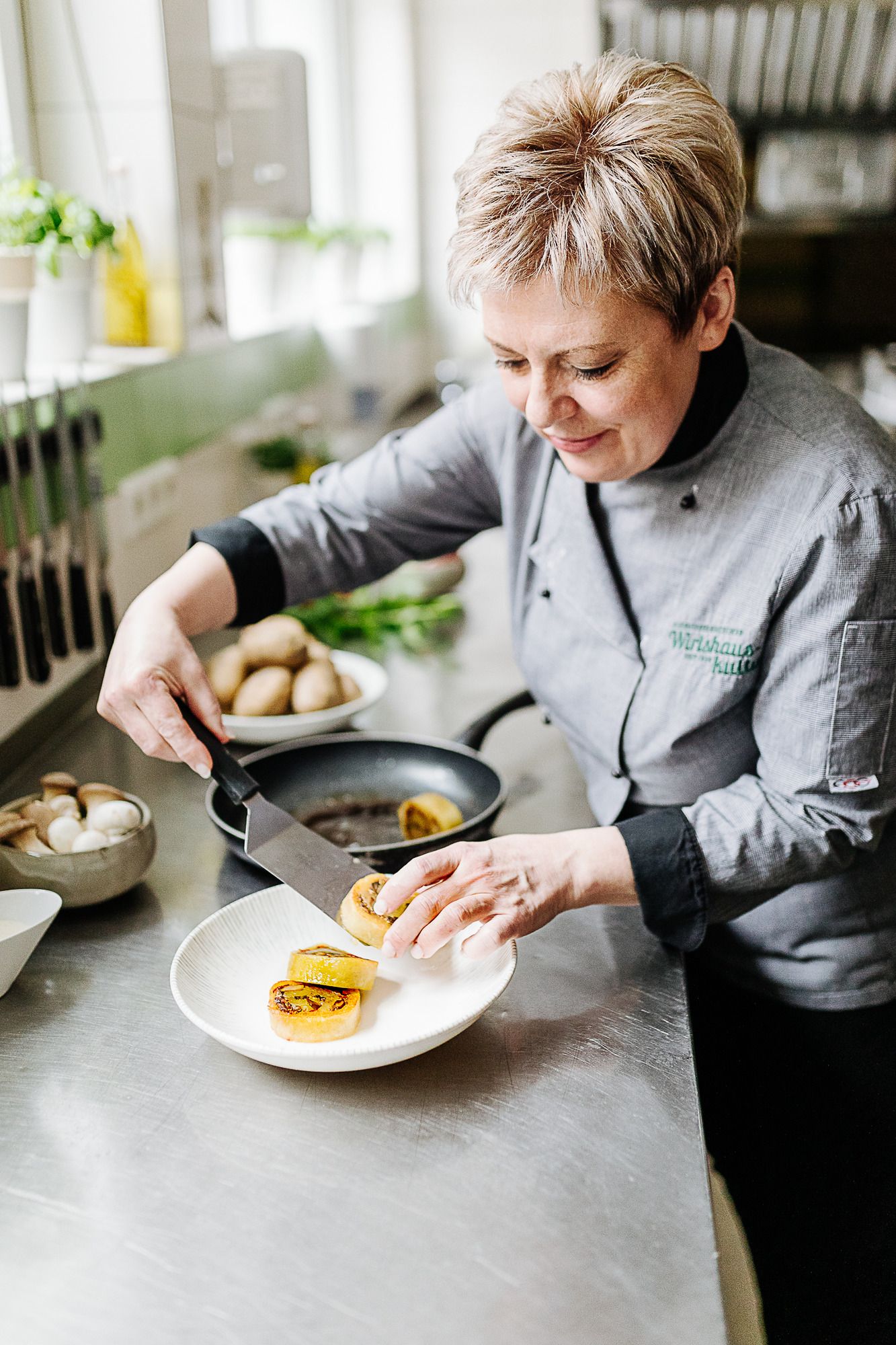 Eine Frau in Kochkleidung richtet Essen auf einem Teller an.