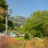 Ein Alpengarten mit Liegest&uuml;hlen, B&auml;umen und einem Berg im Hintergrund.