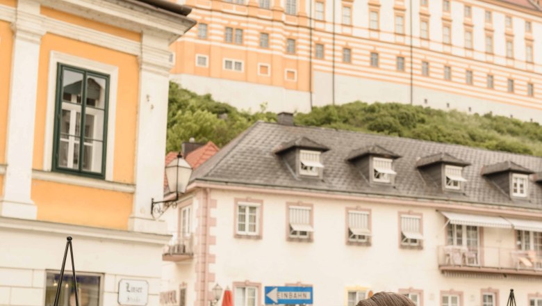 Zwei Frauen genießen Eisbecher im Gastgarten mit Blick auf das Stift Melk.