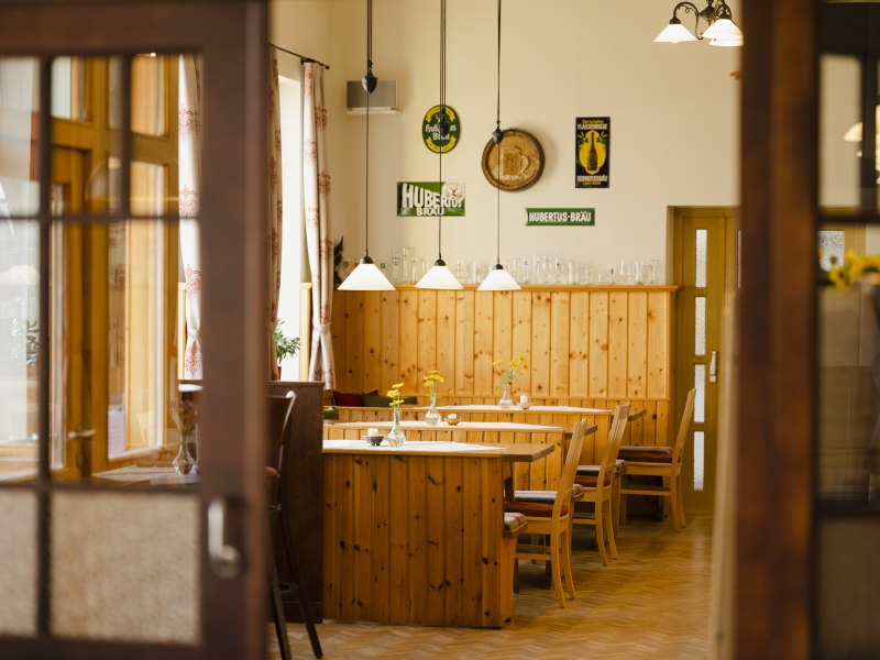 Innenansicht eines traditionellen &ouml;sterreichischen Wirtshauses mit Holzm&ouml;beln und dekorativen Schildern an der Wand.