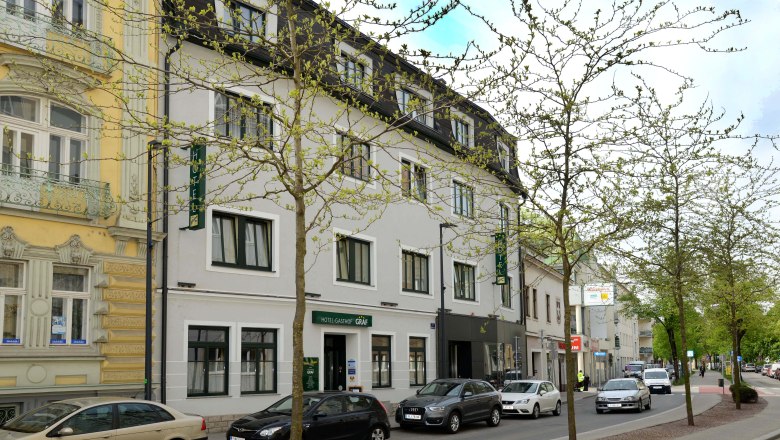 Stra&szlig;enansicht des Hotel-Gasthof Graf mit parkenden Autos und B&auml;umen.