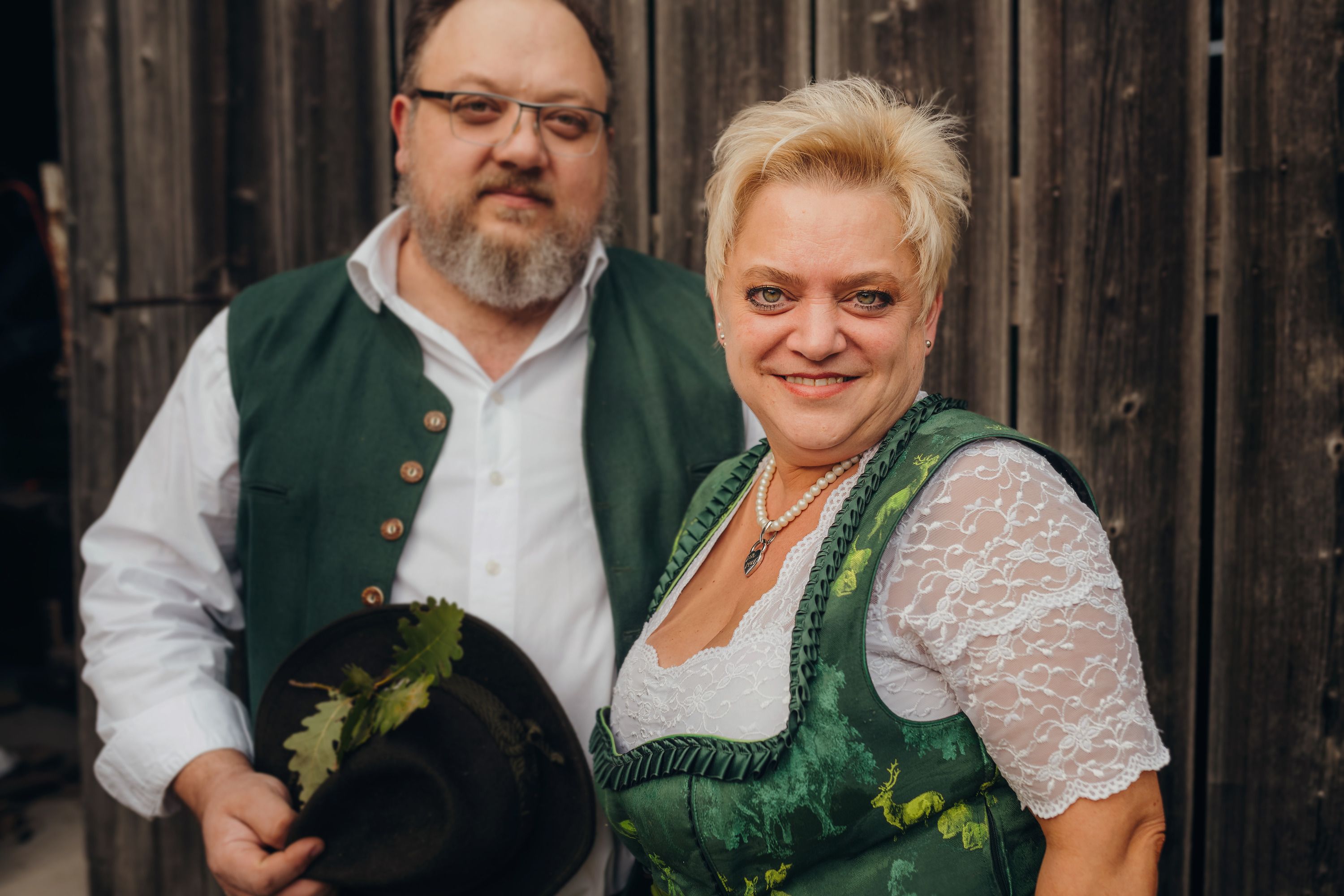 Ein Mann und eine Frau in traditioneller Tracht vor einer Holzwand.