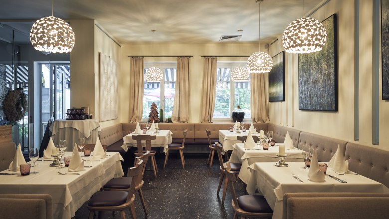 Elegantes Restaurant mit gedeckten Tischen, modernen Lampen und Kunst an den Wänden.