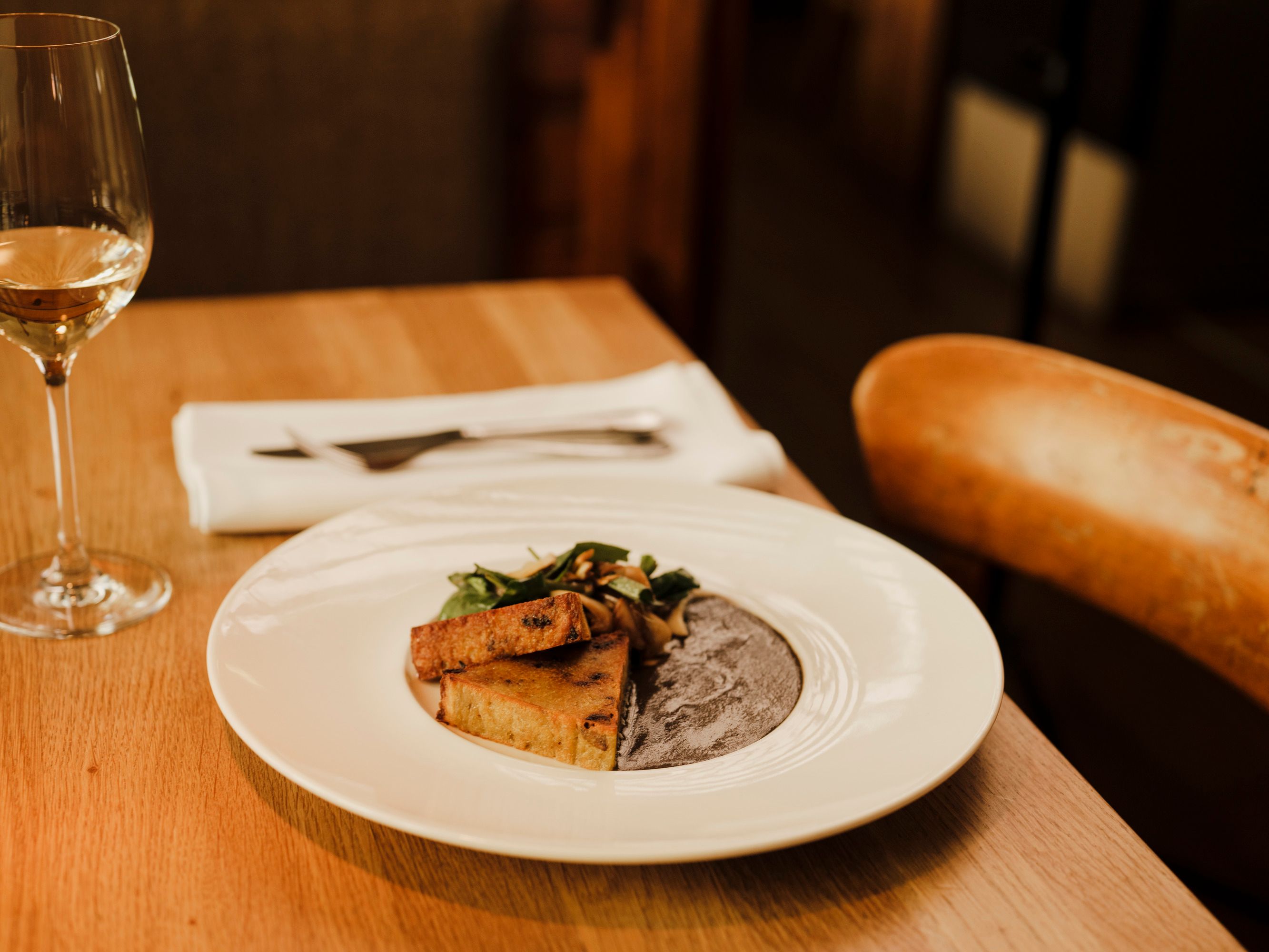 Elegantes Gericht mit Wein auf Holztisch in stilvollem Restaurant.