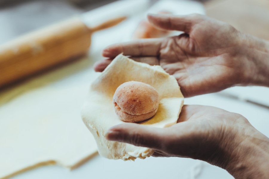 H&auml;nde formen einen Teig um eine Marille.