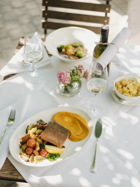 Elegantes Mittagessen im Freien mit Fisch, Gem&uuml;se und Wei&szlig;wein.