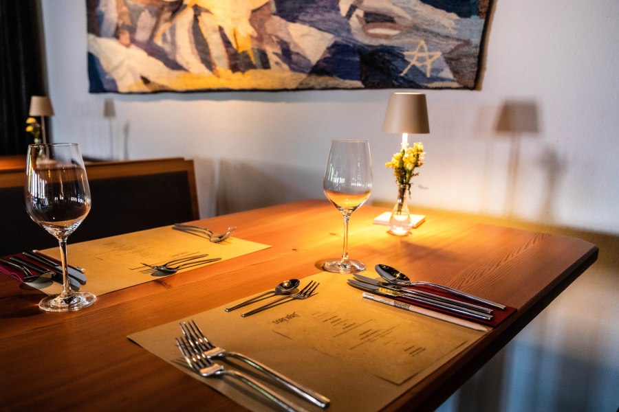 Eleganter Tisch in einem Restaurant mit Weingl&auml;sern, Besteck und Blumen.