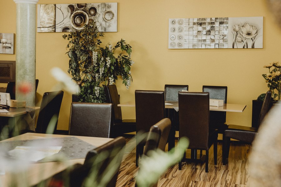 Gem&uuml;tliches Restaurant mit gelben W&auml;nden, Pflanzen und moderner Kunst.