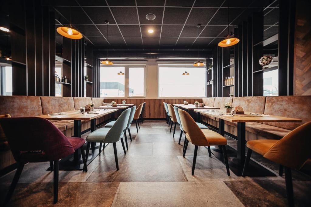 Leeres, modern eingerichtetes Restaurant mit Tischen, gepolsterten Stühlen und warmen Pendelleuchten. Titel: Egino.