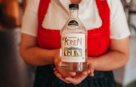 Person h&auml;lt eine Flasche Krenn Gin mit Auszeichnungsetikett.