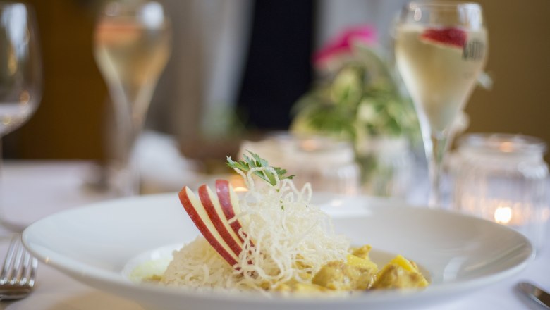 Ein Teller mit Reis, Apfelscheiben und einer Garnitur auf einem gedeckten Tisch.