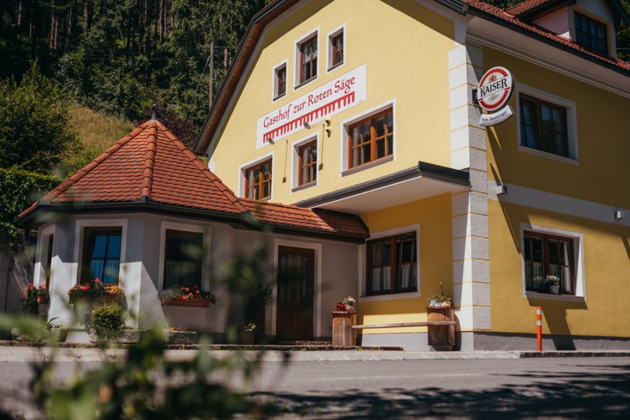 Gelbes Geb&auml;ude mit der Aufschrift 'Gasthof zur Roten S&auml;ge' und einem Kaiser-Bierschild.