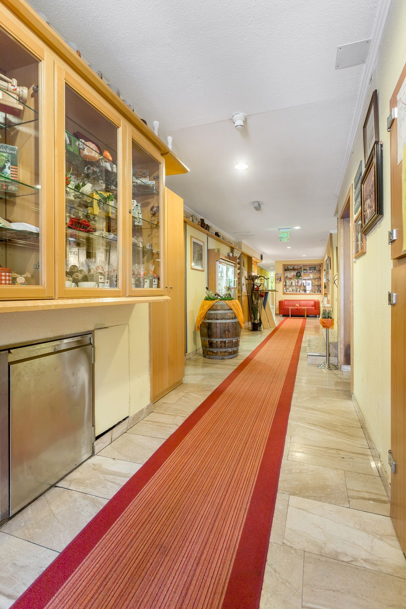 Ein Hotelkorridor mit rotem Teppich, Vitrinen und Dekorationen.