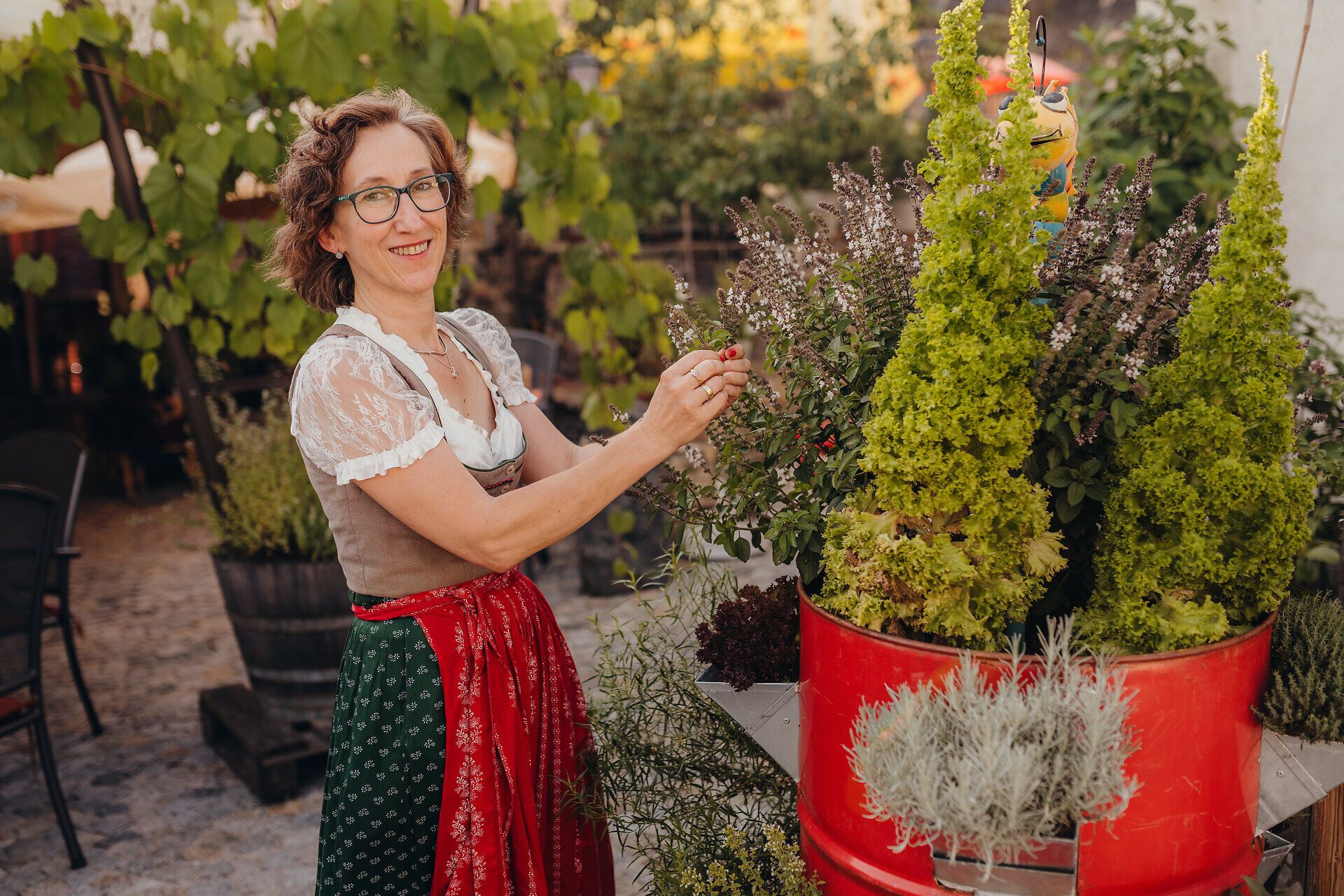 Inmitten einer blühenden Oase aus Kräutern und Pflanzen strahlt die Wirtin Andrea Gruber eine herzliche Gastfreundschaft aus. Die sanften Farben der Natur und die frische Luft laden dazu ein, die kulinarischen Köstlichkeiten der Region zu genießen und die Seele baumeln zu lassen.
