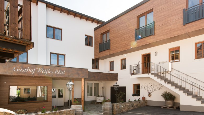 Au&szlig;enansicht eines Gasthofs mit Holz- und wei&szlig;en Fassaden, Treppe und Dekorationen.