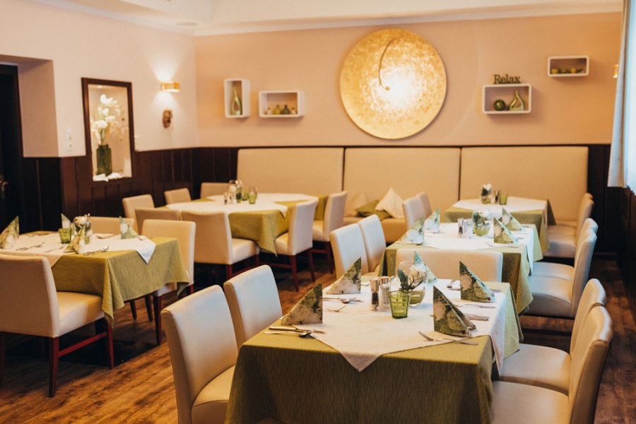 Elegantes Restaurant mit gedeckten Tischen und gr&uuml;nen Tischdecken.