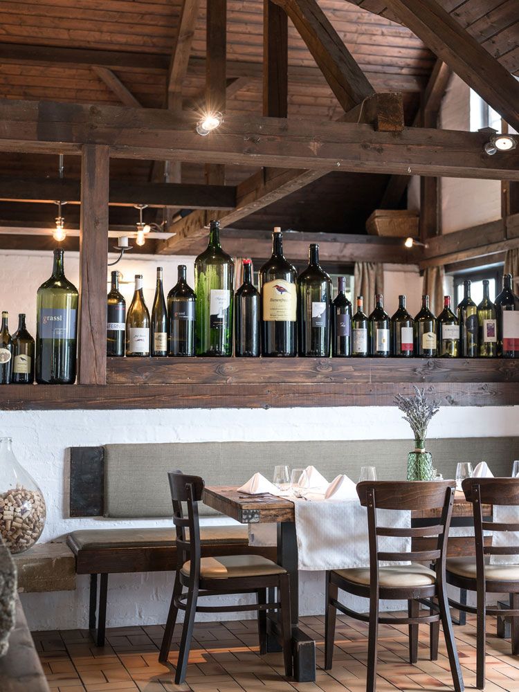 Gemütliches Restaurant mit Holzbalken und Weinflaschen-Dekoration.