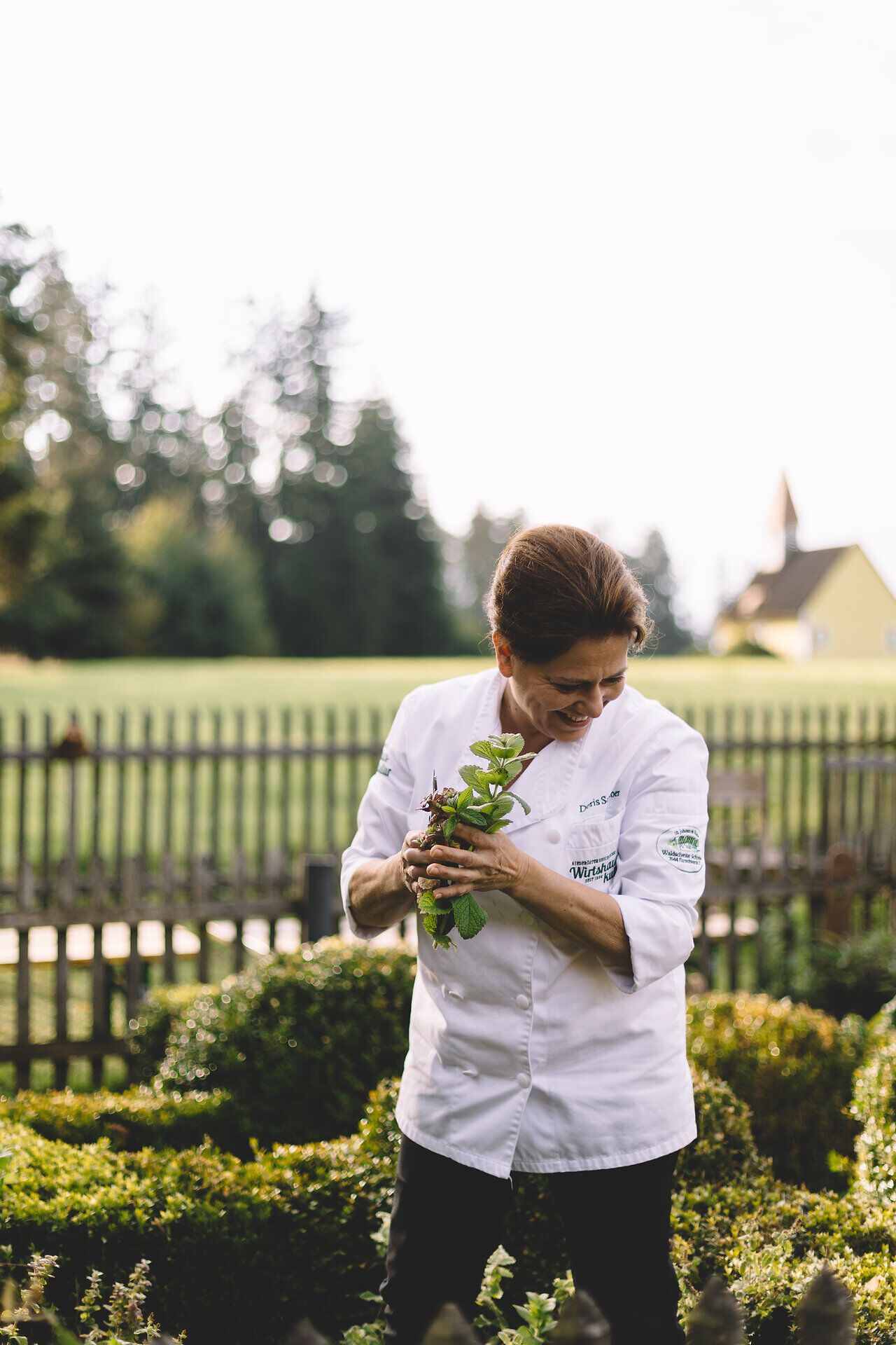 Inmitten der sanften Hügel des Waldviertels erntet die Wirtin mit Freude frische Kräuter aus ihrem Garten. Die warmen Sonnenstrahlen tauchen die Szene in ein goldenes Licht und verleihen der Umgebung eine einladende Atmosphäre. Hier, wo Natur und Gastfreundschaft aufeinandertreffen, wird jeder Besuch zu einem unvergesslichen Erlebnis.