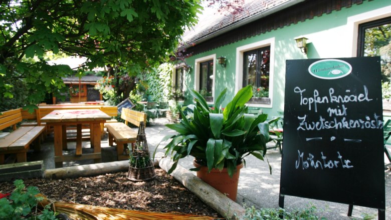 Gemütlicher Gastgarten mit Holzbänken und Tafel im Wirtshaus Bonka, Wienerwald.