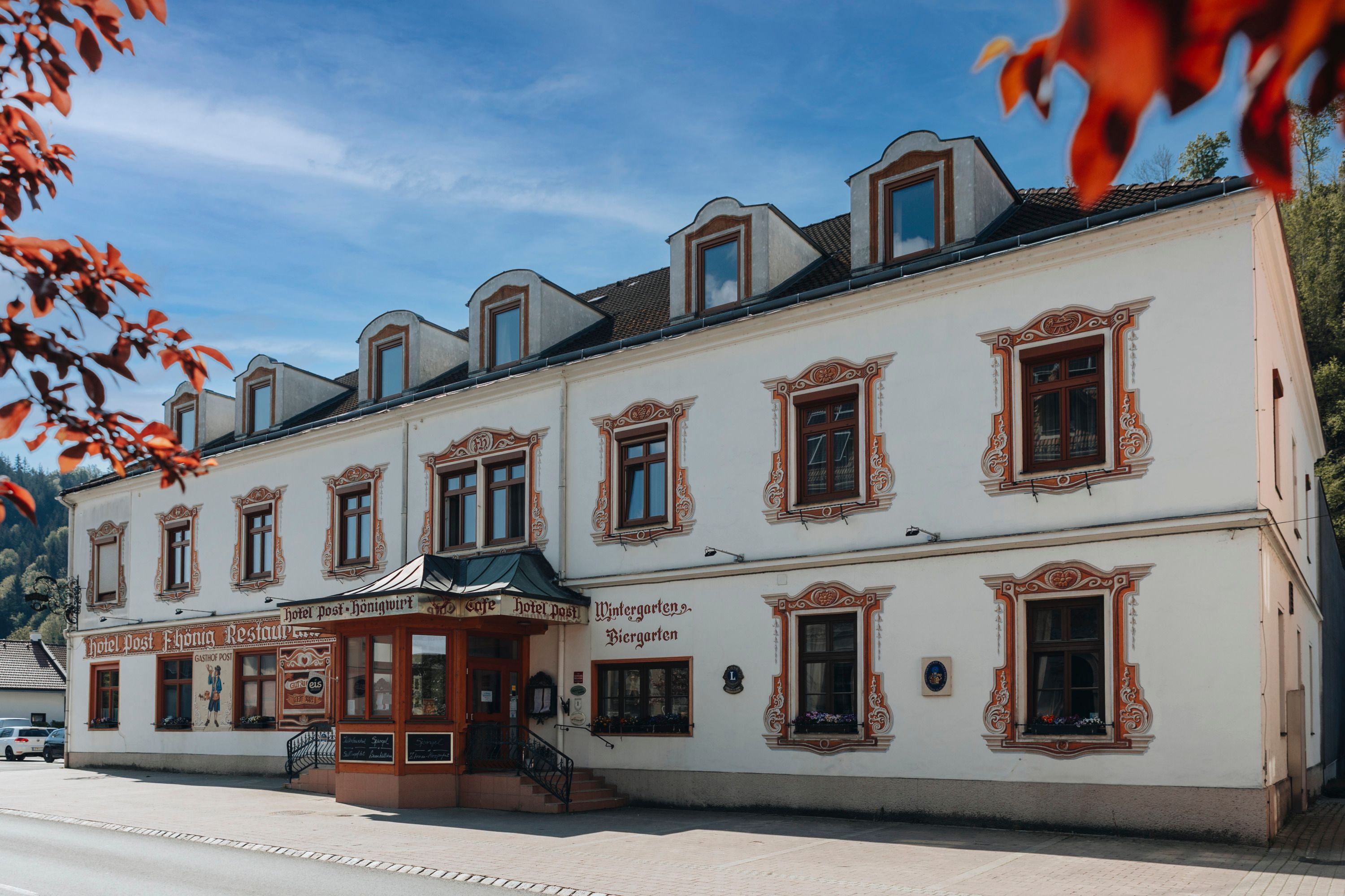 Historisches Gebäude mit dekorativen Fensterrahmen und Schildern für Hotel und Restaurant.