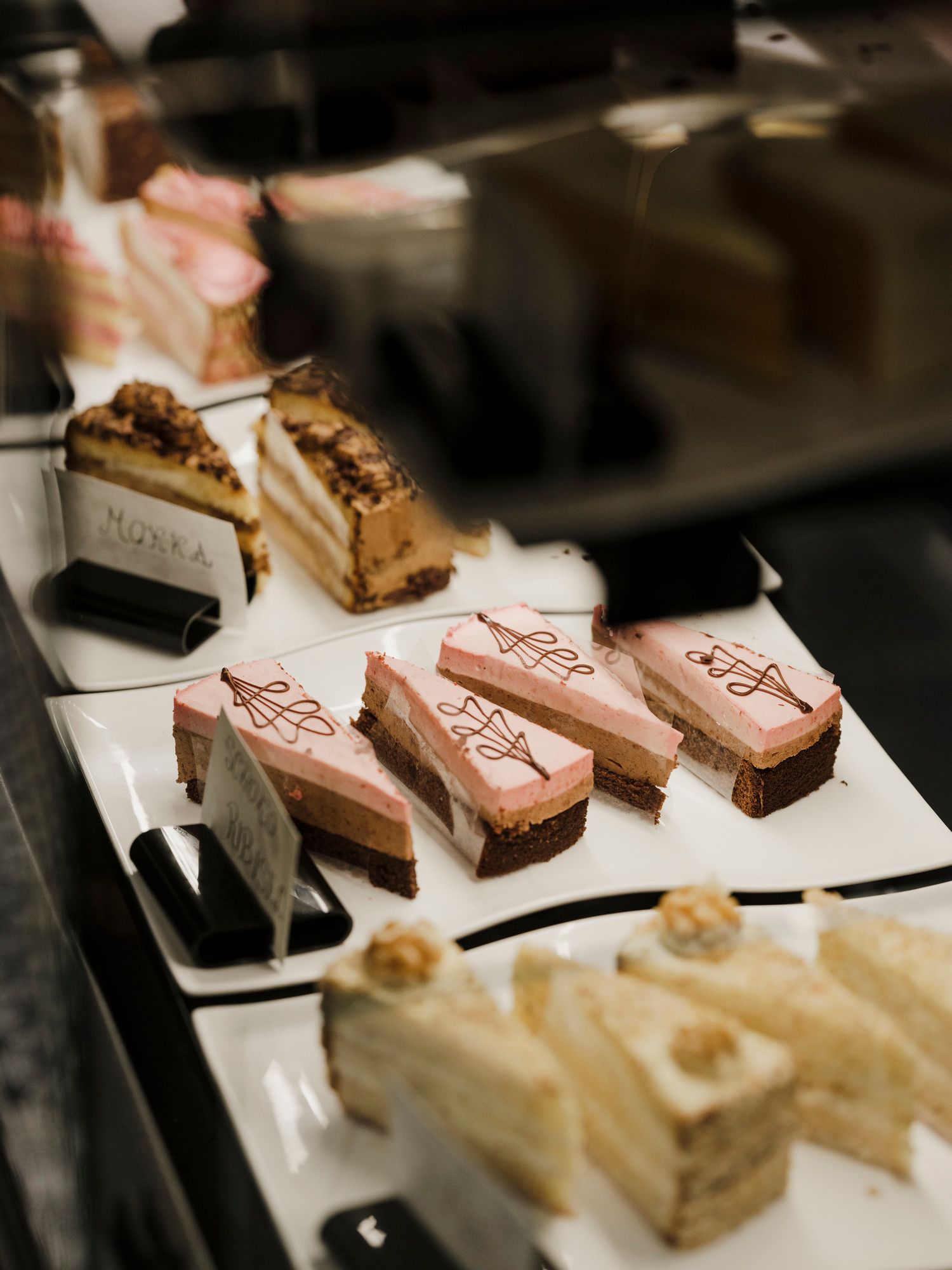 Vitrine mit verschiedenen Kuchenstücken auf weißen Tellern.