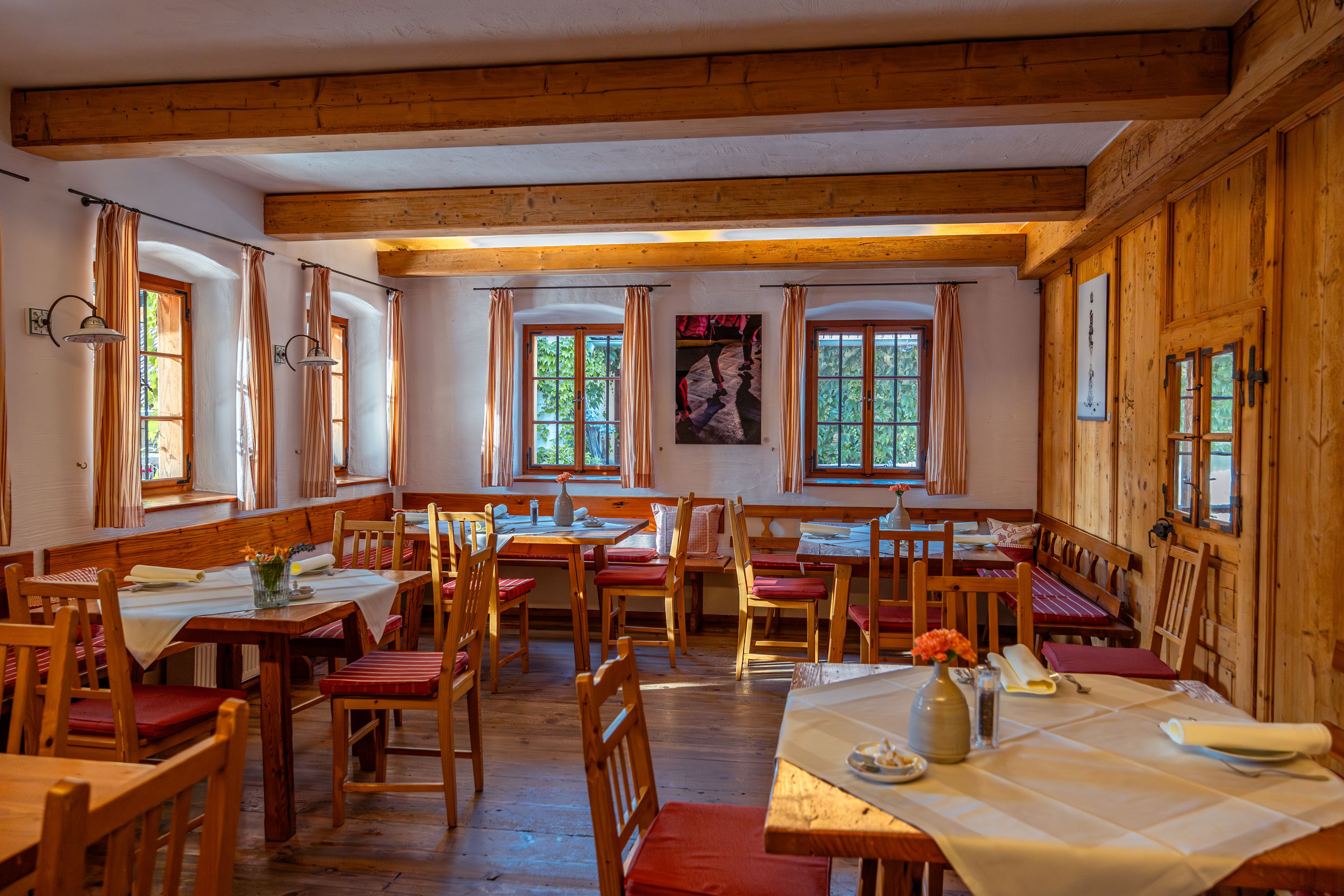 Gemütlicher Gastraum mit Holzmöbeln und gedeckten Tischen.