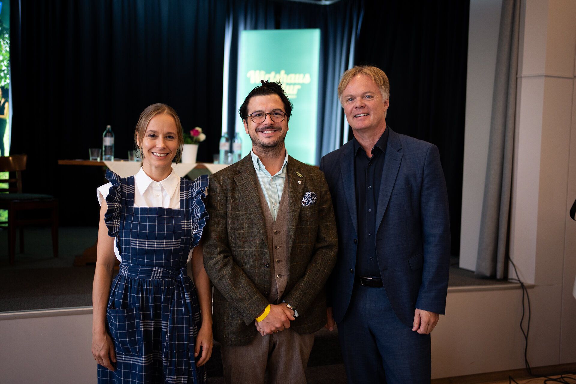 Kira Schinko, Hartmuth Rameder und Michael Duscher (v. l. n. r.) stehen lächelnd gemeinsam vor einer Bühne.