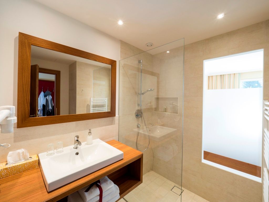 Modern bathroom with wooden details, washbasin, mirror and glass shower.