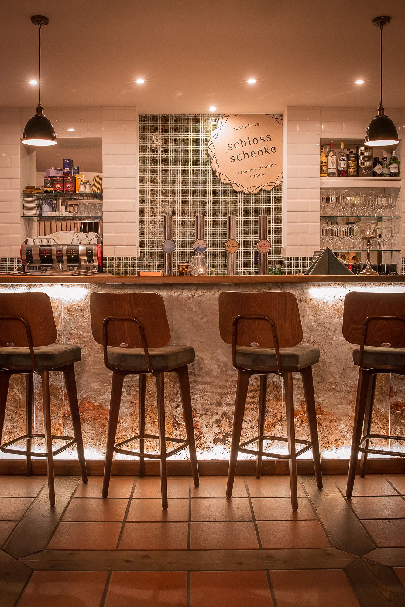 Innenansicht einer stilvollen Bar mit Holzstühlen und beleuchtetem Tresen.