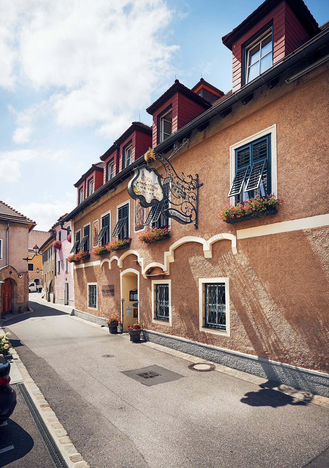 Inmitten malerischer Gassen strahlt das Wirtshaus eine einladende Atmosphäre aus, umgeben von bunten Blumen und historischen Fassaden. Hier können Besucher die traditionelle Wirtshauskultur genießen und sich von der herzlichen Gastfreundschaft verwöhnen lassen.