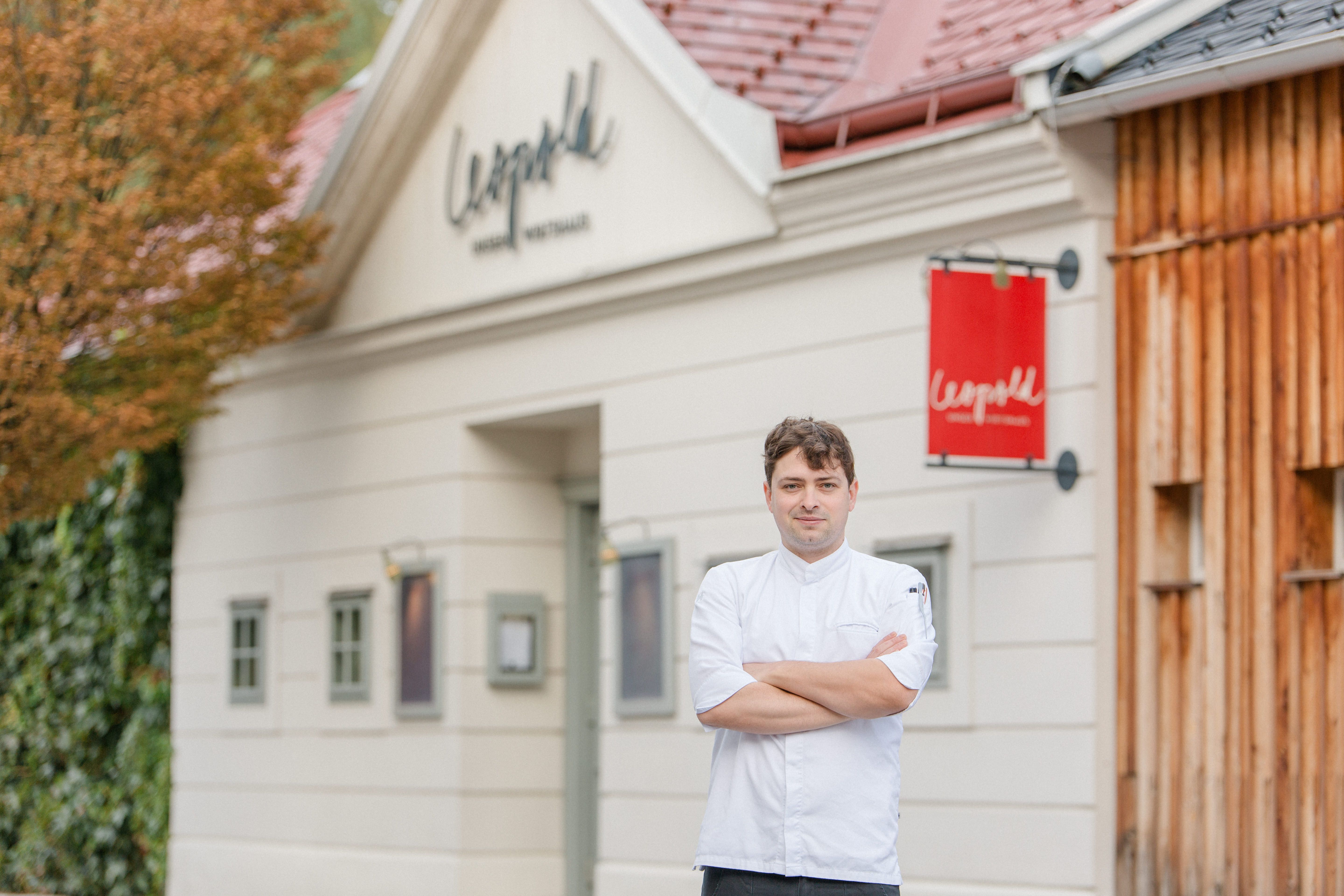 Koch in weißer Uniform vor dem Restaurant Leopold.