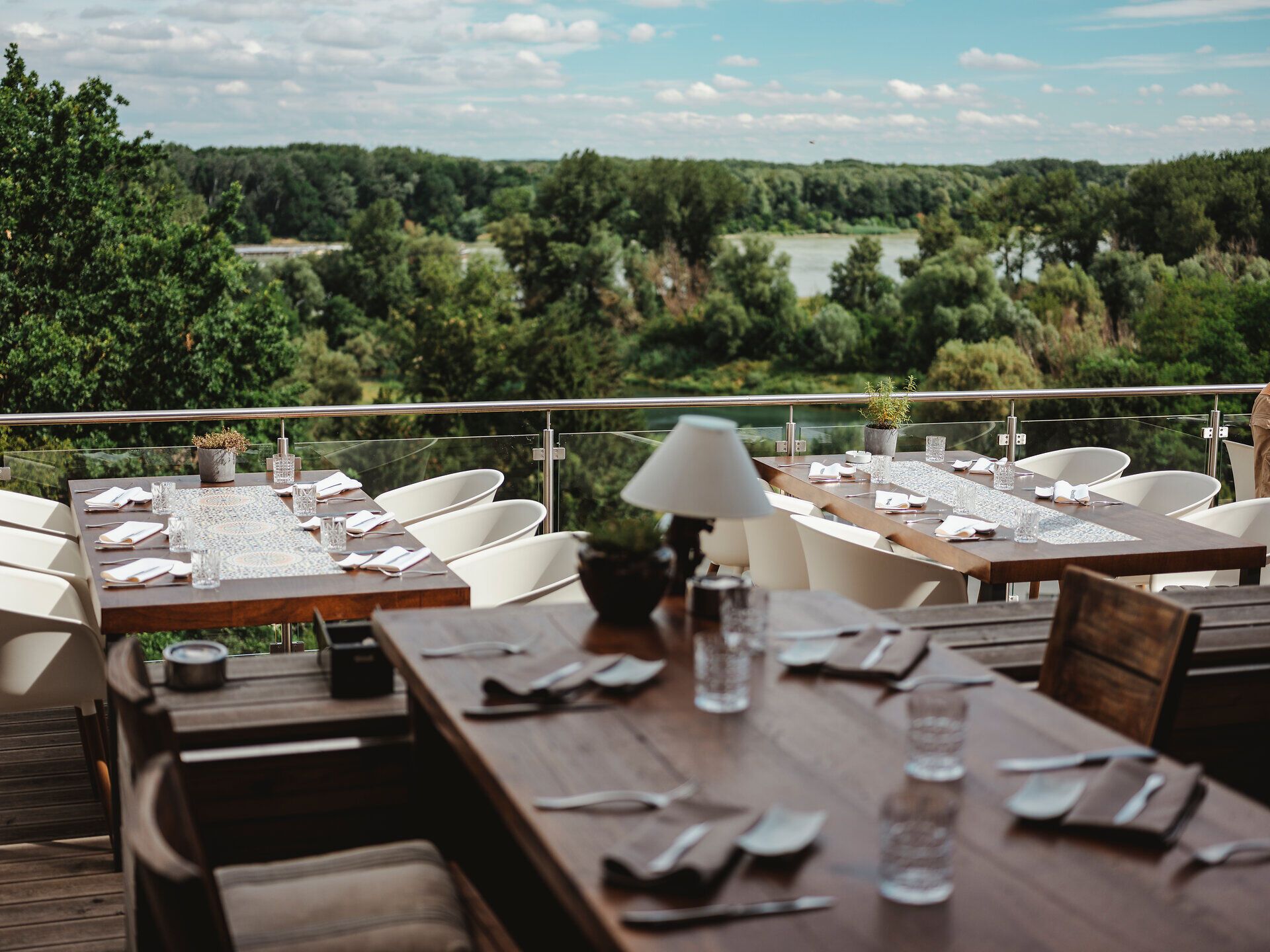 Genießen Sie die entspannte Atmosphäre auf der Terrasse, während Sie den Blick über die sanften Hügel und die glitzernde Donau schweifen lassen. Die stilvoll gedeckten Tische laden dazu ein, regionale Köstlichkeiten zu probieren und die Schönheit der Natur in vollen Zügen zu erleben.